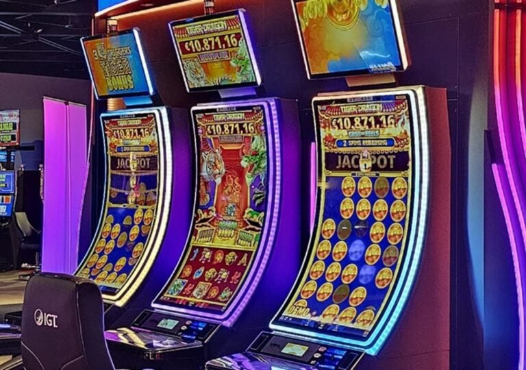 LED 조명과 대형 커브드 스크린이 적용된 IGT 슬롯머신들이 전시장에 배치된 모습