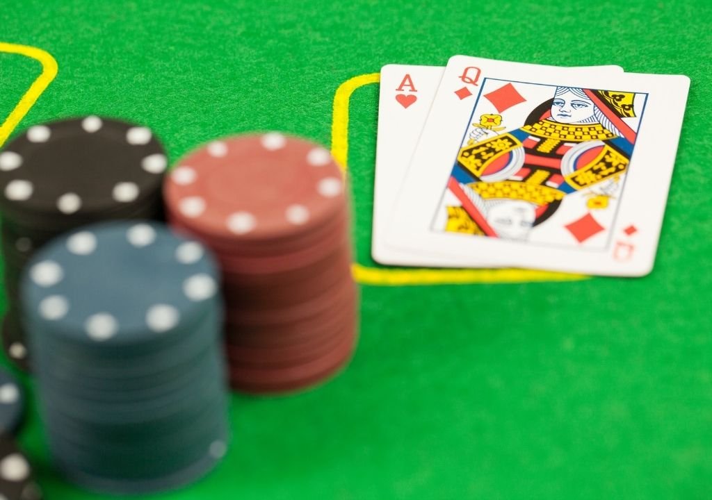 블랙잭 테이블에서 에이스와 퀸으로 완성된 블랙잭 패(내추럴 21)를 보여주는 이미지