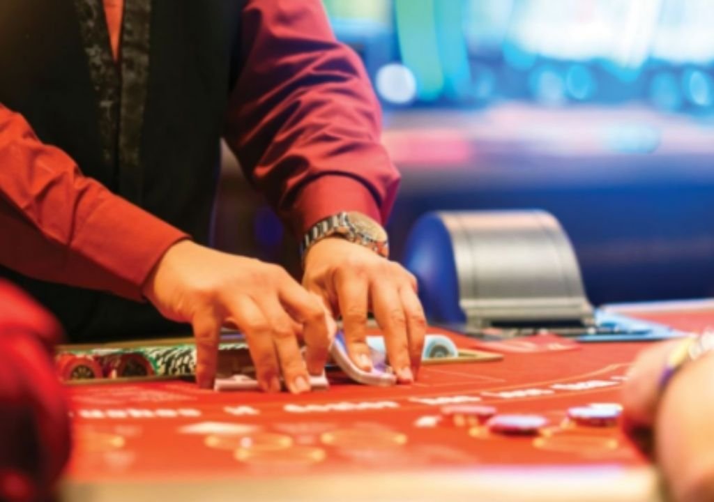 “카지노 딜러가 테이블 위에서 칩과 카드를 정리하는 모습 — 강원랜드와 MGM 오사카의 경쟁을 상징하는 장면”