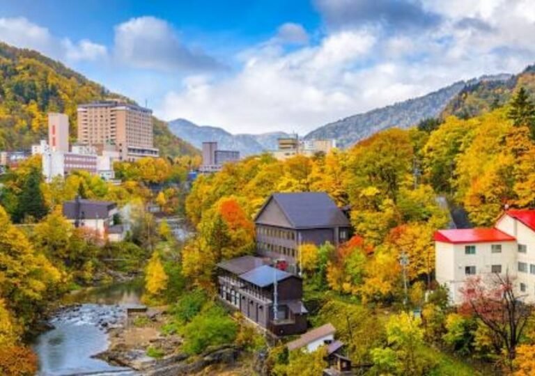 단풍이 물든 산악지대와 도시 건물이 어우러진 일본 홋카이도 가을 전경